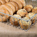 A Clipper Mill iron wire pastry basket filled with bagels and muffins on a counter.