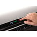 A hand pressing a button on a Fellowes Jupiter 2 laminator.