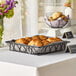 A black Clipper Mill square wire basket on a table with croissants.