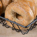 A Clipper Mill gray square wire basket with a bagel inside.