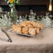 A Clipper Mill chrome plated iron square wire basket with croissants on a table.