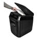 A person holding a black Fellowes AutoMax 130C paper shredder over a piece of paper.