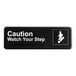 A black sign with white text that says "Caution Watch Your Step"