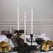 A table with bread, wine glasses, and white Hyoola taper candles.