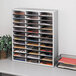 A white literature organizer with many different sections holding file folders.
