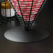 A black iron wire basket with red and white checkered paper inside.