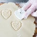 A person using an Ateco strawberry pastry cutter to cut out cookies.