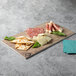 A Thunder Group Sequoia Faux Wood Melamine serving board with meat and crackers on it.