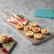A Thunder Group Sequoia faux wood melamine serving board with appetizers on a table.