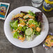 A Carlisle white melamine plate with a salad and crackers on it.