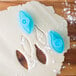 Two blue plastic Ateco lily petal plunger cutters and cookie dough with shapes.