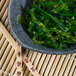 A Biseki blue stoneware bowl filled with seaweed salad on a table.