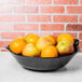 A black GET Siciliano bowl filled with oranges on a table.