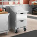 A stainless steel 2-drawer mega top refrigerated sandwich prep table on wheels.