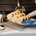 A person using a Clipper Mill clear plastic food basket liner to display a bagel with sprinkles.