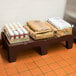A brown Cambro dunnage rack holding brown bags of food and a bag of salt.