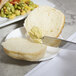 A 10 Strawberry Street pearl stainless steel dinner knife spreading butter on a piece of bread.
