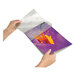 A hand using a Fellowes 5200509 laminating pouch to protect a purple and yellow piece of paper.