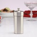 A silver stainless steel salt mill on a white table.