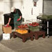 A man in a green apron using a Cambro brown solid top bow tie dunnage rack to store tomatoes.