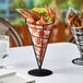 A black metal cone shaped basket with seafood on a table.