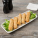 A Tuxton eggshell china tray of fried spring rolls.