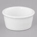 A close up of a Tuxton white china ramekin on a gray surface.
