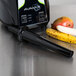 A black AvaMix tamper next to a blender with bananas and other fruit on a table.