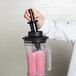 A person using a black AvaMix tamper in a blender.