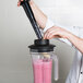 A person using a black AvaMix tamper in a blender on a counter to make a smoothie.