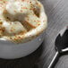 A white Tuxton porcelain bowl filled with French onion soup topped with melted cheese.