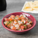 An assorted color Tuxton sauce dish filled with salsa on a wood table.