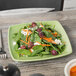 A Tuxton decorated square china plate with salad on a table.