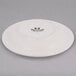 A Tuxton brown speckle china saucer with black text on it.