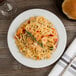 A Libbey medium rim porcelain plate with pasta, shrimp, and vegetables.