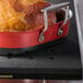 A cooked ham in a black perforated Tablecraft carving station template.