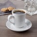 A Libbey Basics tall white porcelain cup of coffee on a saucer.