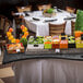 A Tablecraft translucent black metal serpentine swirl table cover on a buffet table with food on it.