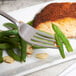 A Bon Chef stainless steel dinner fork on a plate with fish and green beans.