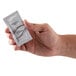 a hand holding a small white packet