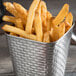 A Tablecraft stainless steel square fry cup filled with french fries on a table.