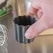 A person holding a small metal Matfer Bourgeat Cannele mold.