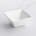 An Acopa bright white square bowl on a white surface.