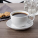 A Libbey bright white porcelain low cup of coffee on a saucer with cookies.