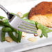 A Bon Chef stainless steel dinner fork on a plate with food.