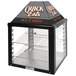 A black and silver Global Solutions by Nemco countertop hot food merchandiser with a sign on it.
