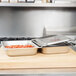 A white counter with two Vollrath hinged flat pan covers on trays of food.