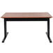 A Luxor stand up desk with a black base and wooden top.