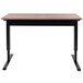 A Luxor black stand up desk with a wooden top and black legs.