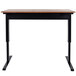 A Luxor black stand up desk with a brown top and black legs.
